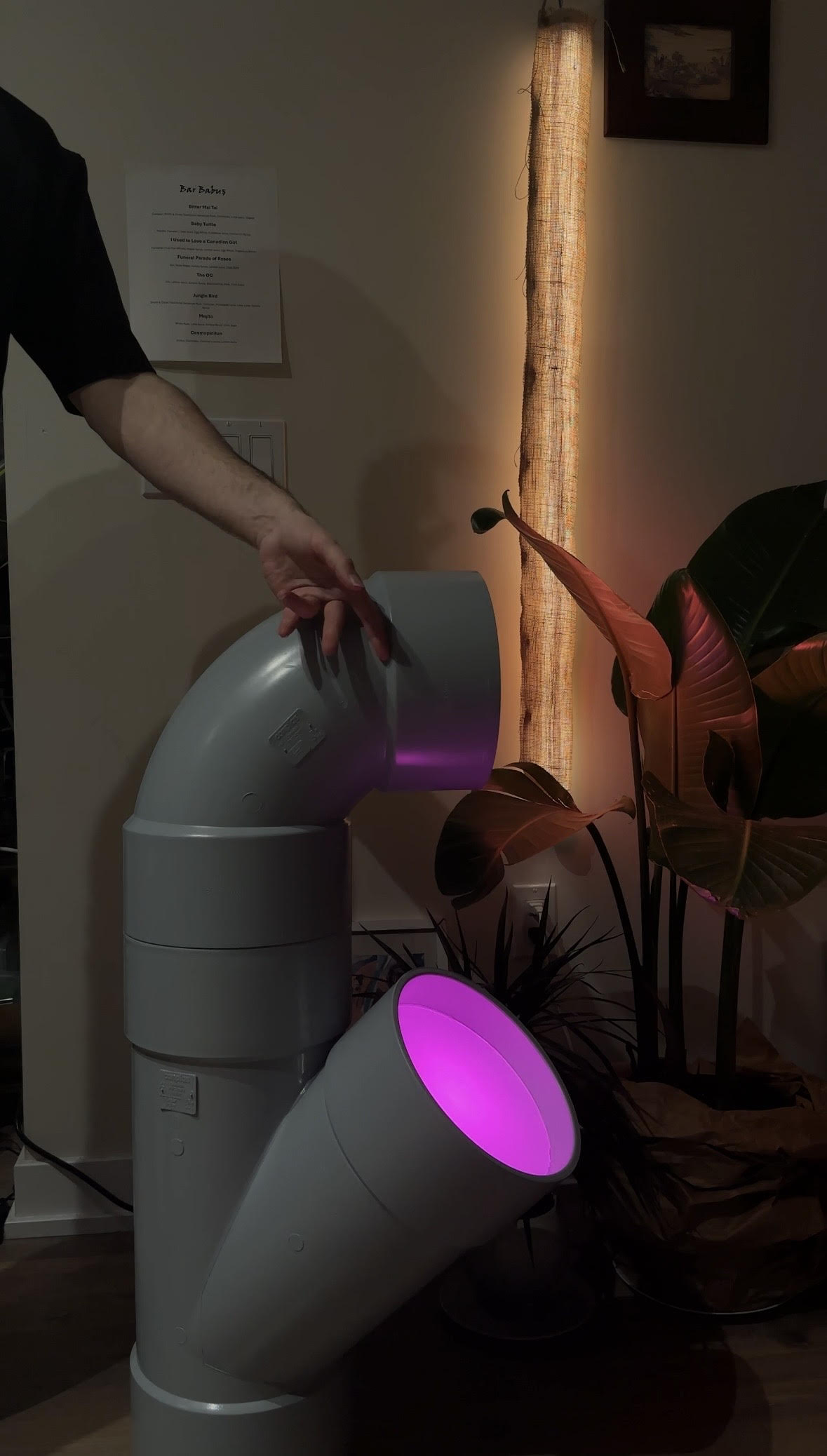 Pipe light in a room: PVC WYE and elbow fittings with purple accent lighting; hand adjusting the rotating elbow